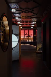 A sophisticated bar area with a long counter, bottles, wine glasses, and decorative elements, set against a dark background