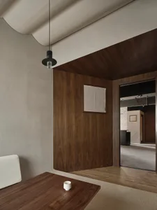 Cozy living area with wooden floors and walls, featuring a couch, dining table, chair, and coffee cup