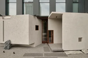 A modern building with a white exterior, large windows, and two doors, conveying a sense of openness and functionality