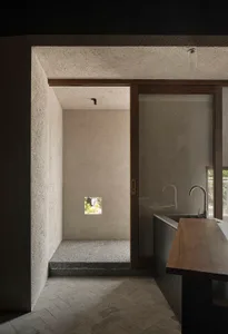 Modern bathroom with two toilets, a sink, and a shower, featuring grey tiles on the walls and floors, and well-lit with a comfortable atmosphere