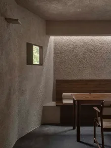 A modern dining area with a wooden table and chairs, well-lit with natural light