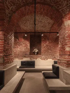 Modern interior design concept featuring a brick building with a stone archway, black couches, and a decorative vase in a large open area