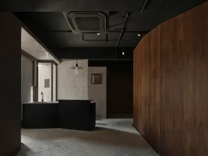 A modern hotel lobby with a black countertop, sink, clock, chairs, and vases, designed for guest comfort and convenience
