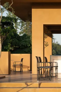 A patio dining area with a metal table surrounded by four wooden chairs in a relaxed and inviting outdoor setting
