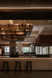 Warm and inviting restaurant interior with wooden beams, tables, chairs, and cups, creating a cozy atmosphere for dining and socializing