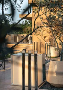 An inviting outdoor seating area with two central poles, well-lit and furnished with chairs and dining tables