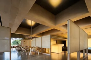 Modern restaurant interior with multiple dining tables, chairs, and natural light, featuring a combination of white and brown tones on the walls