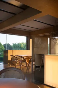 A modern living space with a wooden dining table surrounded by chairs, well-lit with natural sunlight coming in through windows