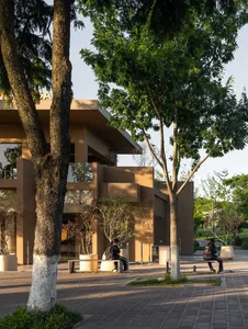 一座磚牆外觀的經典建築，周圍環繞樹木與戶外座位區，人們在此放鬆身心，享受周遭環境