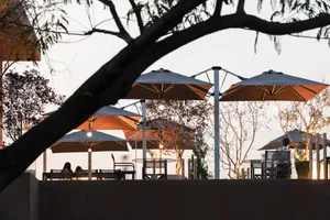 An outdoor dining area at night with multiple tables and chairs under umbrellas, creating a cozy and inviting atmosphere for guests to relax and socialize