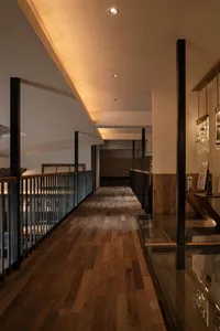 A well-lit hallway in a museum or gallery with wooden floors and walls, featuring several artworks on display