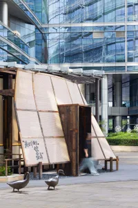 A woman walks past a modern building with glass windows and a contemporary design in a busy urban environment