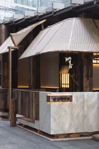A warm and inviting Asian restaurant with wooden walls, stone countertops, and umbrella-like structures providing shade