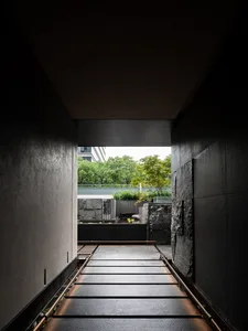 A modern hallway with concrete walls and a metal railing, featuring two doors and a perspective view of the interior space