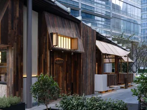 Cozy restaurant interior with wooden walls, ceiling, and potted plants, featuring a large window for natural light