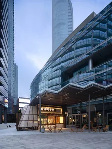 熱鬧都市街景，搭配玻璃建築立面、戶外座位區，以及人們享受氛圍