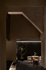 Cozy cafe interior with a wooden table, chairs, potted plants, and a vase, featuring a warm and inviting atmosphere with brown and white tones