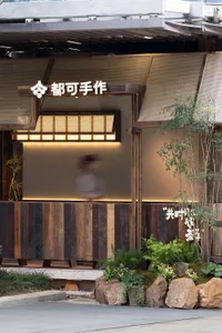 A woman walks through the entrance of an Asian restaurant with a warm and inviting atmosphere, surrounded by wooden elements and potted plants