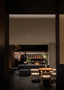 A cozy restaurant dining area with chairs, tables, potted plants, and decorative elements on the walls