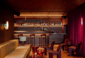 A cozy bar area with a wooden countertop, multiple bottles, and comfortable seating for patrons