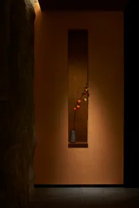 A warm and inviting interior space with a ceramic vase containing flowers and apples on a wall, surrounded by a room with a pleasant atmosphere