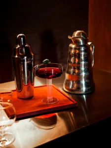 A dimly lit dining area with a metal table, wine glasses, and bowls, creating a cozy atmosphere