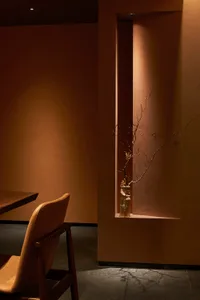 Warm and inviting dining space with a wooden table, two chairs, and a vase, lit by natural light
