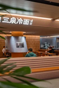 A modern Asian restaurant with wooden chairs and tables, Chinese characters on the walls, and a well-lit atmosphere