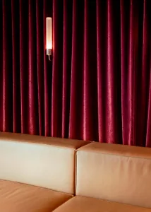 Cozy living room with two couches, chairs, and a red velvet curtain wall, creating a warm and inviting atmosphere
