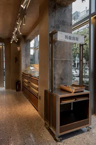 Casual dining space with concrete walls, a modern and industrial feel, and a counter with books, cups, and bowls on display