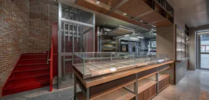Industrial kitchen with glass display case, multiple ovens, and a professional atmosphere