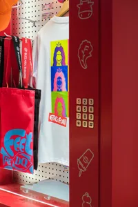 A casual office entrance with a red door, bags, and t-shirts on the wall, creating a sense of organization and personality
