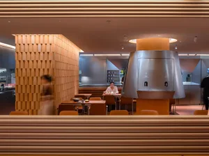 Warm and inviting restaurant interior with wooden walls, tables, and chairs, featuring a cozy atmosphere and a person enjoying their meal