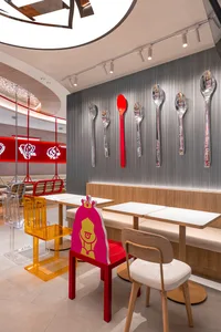A modern restaurant dining area with white tablecloths, chairs, and decorative spoons mounted on the walls, creating a clean and inviting atmosphere