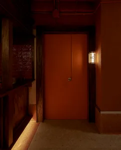 A room with a wooden floor and an orange door with a handle, giving a clean and minimalist appearance