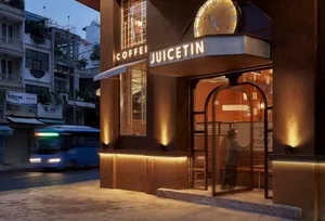 Exterior view of a busy cafe at night with a brown facade, clock, and people outside