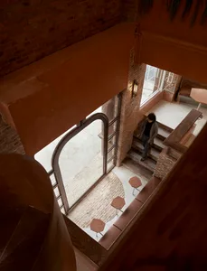 Cozy interior space with a brick building, a staircase, a dining table, chairs, and benches, with a warm and inviting atmosphere