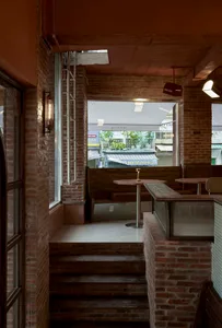 Modern restaurant interior with brick walls, a wooden countertop, and dining tables near windows, featuring a warm and inviting atmosphere