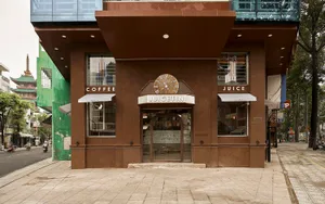 Exterior view of a brown building with a clock on its side, a storefront window, and a cozy atmosphere