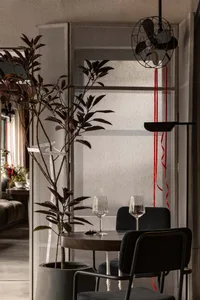 A modern dining space with a table, chairs, wine glasses, a potted plant, and a bowl, creating an elegant and inviting atmosphere