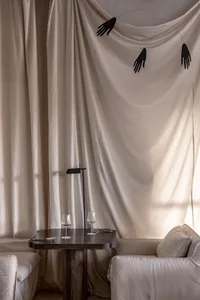 A living area with a couch next to a window, wine glasses on a table, and elegant curtains creating a comfortable and cozy atmosphere