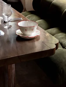 A dining table set with two cups, wine glasses, and spoons, accompanied by a chair in a cozy atmosphere
