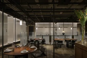 Quiet restaurant interior at night with wood flooring, wine glasses on tables, and elegant design elements