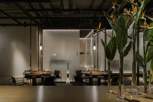 Sophisticated restaurant interior with wooden furniture, wine glasses, and potted plants, set in a well-lit space with a warm ambiance