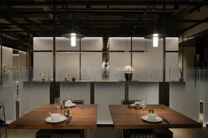 Sophisticated restaurant interior with wooden tables, glass partitions, and modern design elements, featuring wine glasses and cups on two dining tables