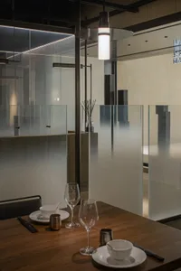 A modern restaurant interior with glass walls, a dining table, wine glasses, and a bottle, featuring a clean, bright, and inviting atmosphere