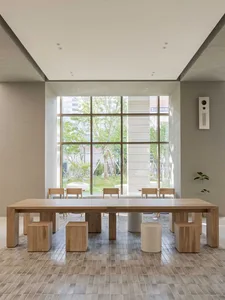 Open living area with a wooden dining table, multiple chairs, and potted plants, creating a warm and inviting atmosphere