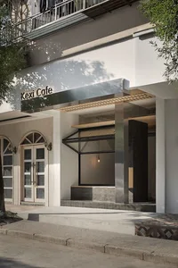 Exterior view of a modern cafe with a white facade, large windows, and a minimalist style