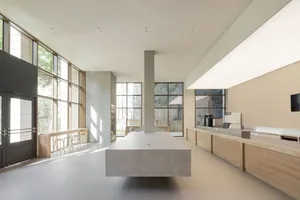 Open modern kitchen and dining area with a large island, multiple windows, and a dining table near the kitchen