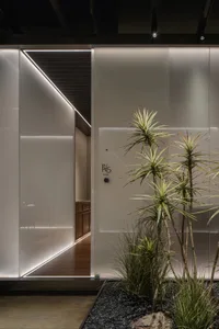 A modern hallway with white walls, a clock, and two potted plants, creating a clean and bright atmosphere
